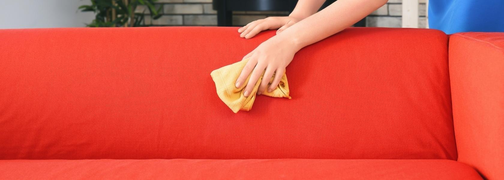 woman cleaning red sofa with a rag