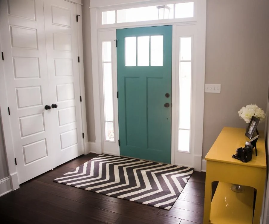 foyer with teal door and small rug