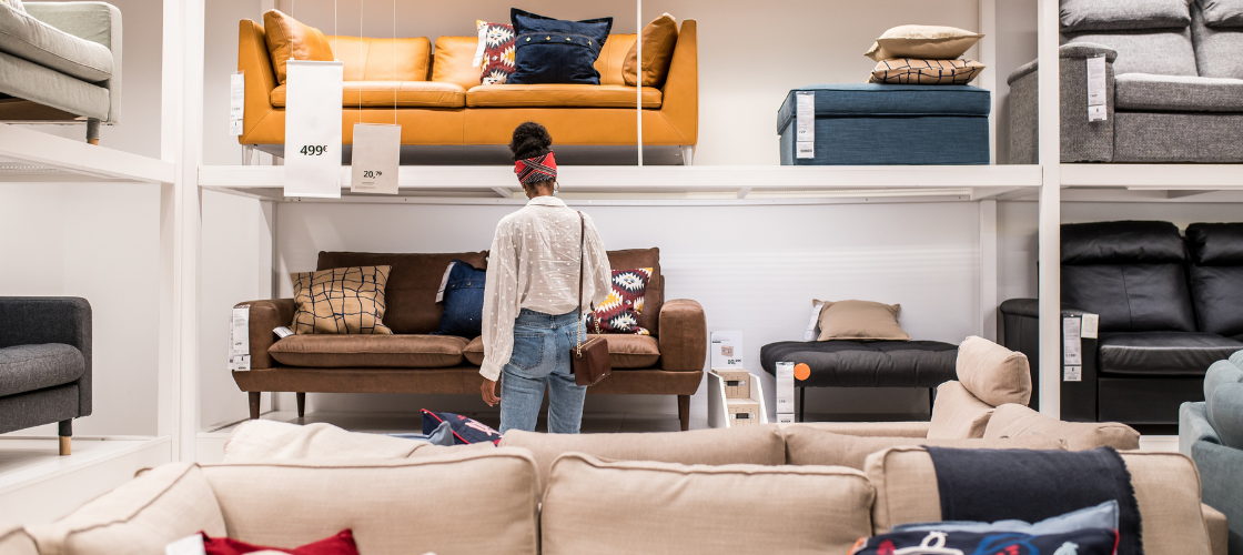 woman in white shirt and blue jeans furniture shopping with several rows of sofas, loveseats, chairs and ottomans