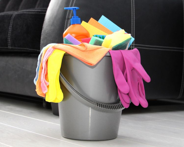 cleaning bucket with different cloths, rags, sponges and cleaning gloves in it