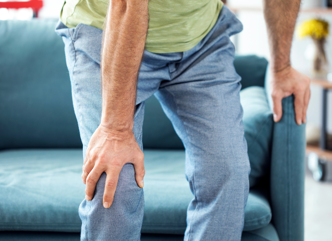 older man grabbing knee as he gets up off of a very low sofa