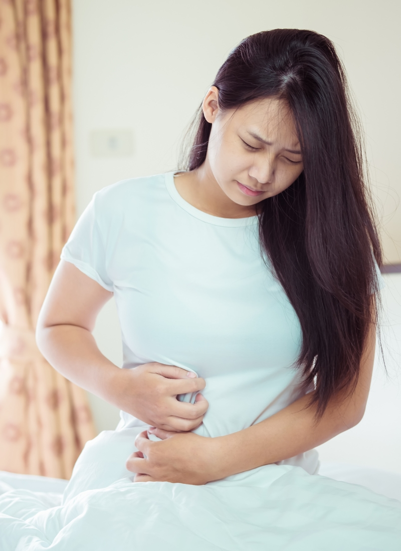 woman-holding-upset-stomach-in-bed-digestion-gi-issues
