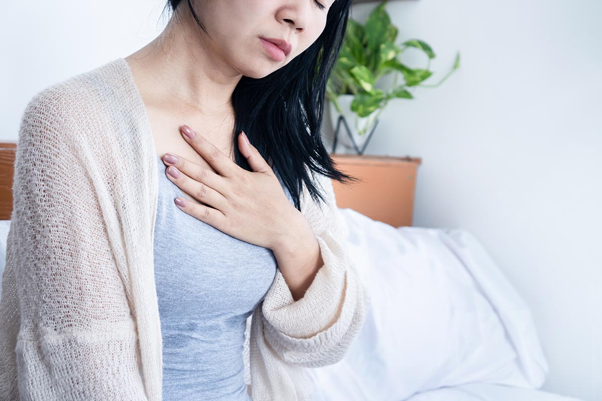 woman-holding-her-chest-in-bed-heartburn-acid-reflux