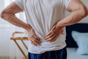 man holding back from back pain during sleep